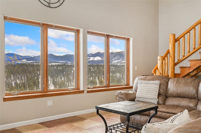 living area with a wealth of natural light, a mountain view, stairs, and baseboards