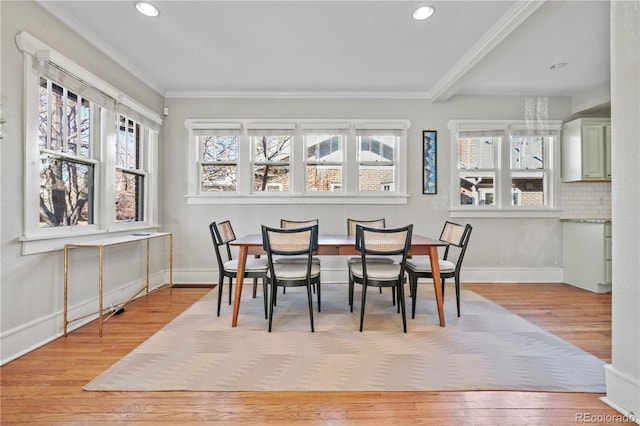 dining space with ornamental molding and light hardwood / wood-style flooring