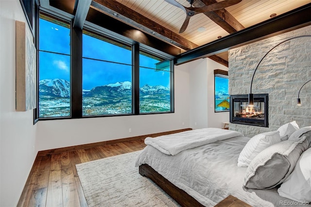 65 Aerie Dr, Silverthorne, CO 80498 - bedroom featuring multiple windows, wood finished floors, a stone fireplace, and a wooden ceiling with exposed beams