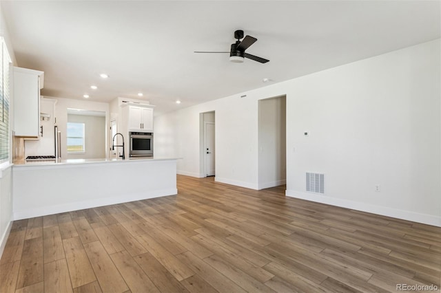 unfurnished living room with recessed lighting, wood finished floors, a ceiling fan, visible vents, and baseboards