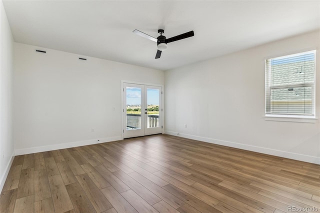 empty room featuring baseboards, visible vents, a ceiling fan, wood finished floors, and french doors