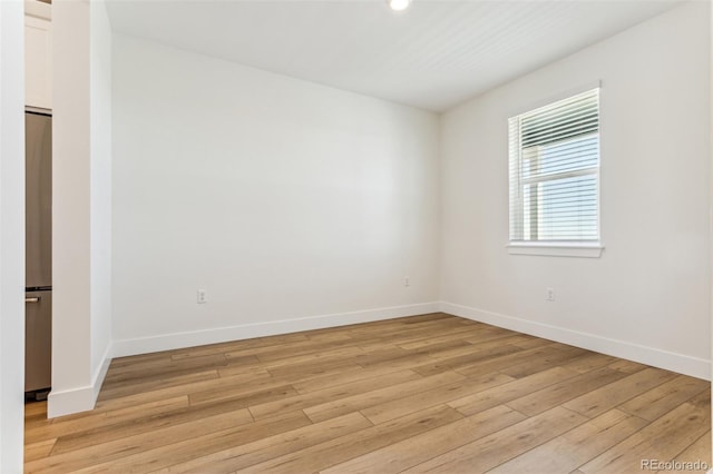 empty room featuring baseboards and light wood finished floors