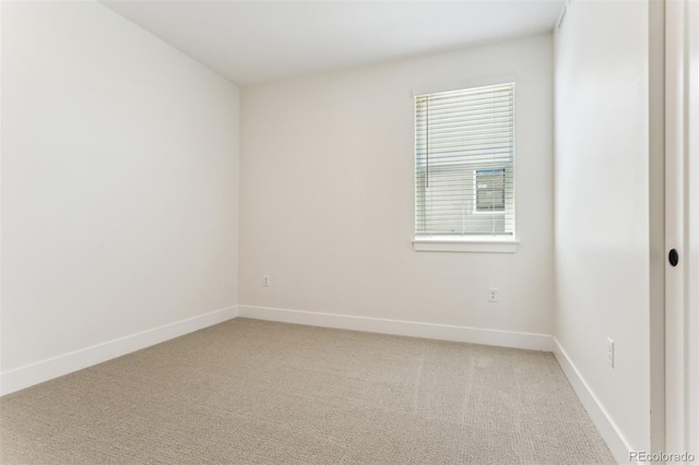 empty room featuring baseboards and light colored carpet