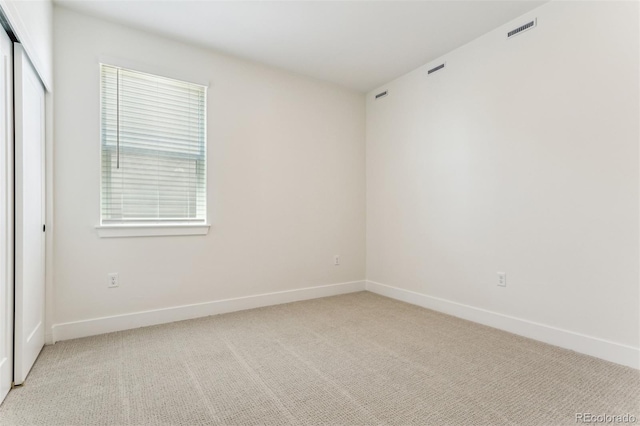 unfurnished room featuring baseboards, visible vents, and light colored carpet