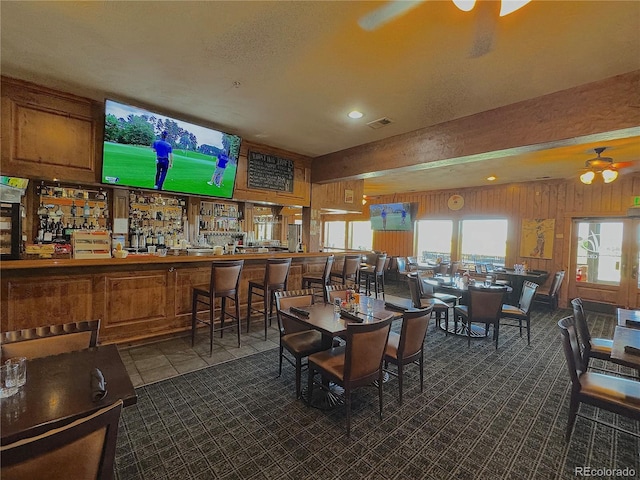 dining area with beam ceiling, wood walls, plenty of natural light, and visible vents