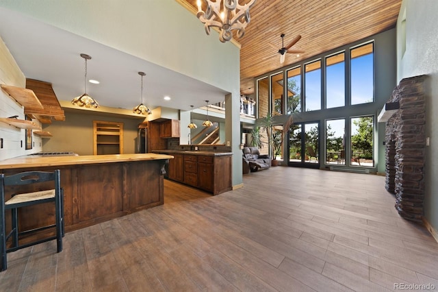 776 Hilltop Rd, Palmer Lake, CO 80133 - kitchen with wood-type flooring, a chandelier, a high ceiling, pendant lighting, and a peninsula