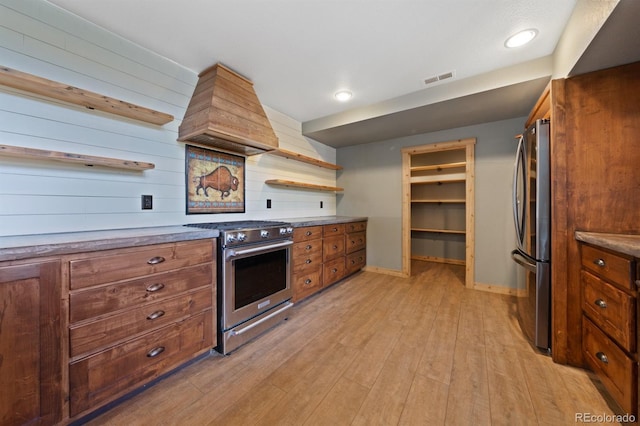 776 Hilltop Rd, Palmer Lake, CO 80133 - kitchen featuring light wood finished floors, brown cabinetry, custom exhaust hood, and stainless steel appliances