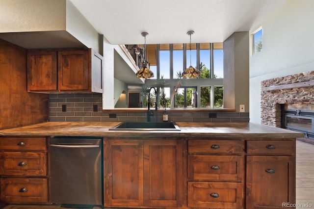 776 Hilltop Rd, Palmer Lake, CO 80133 - kitchen with brown cabinets, a stone fireplace, tasteful backsplash, a sink, and stainless steel dishwasher