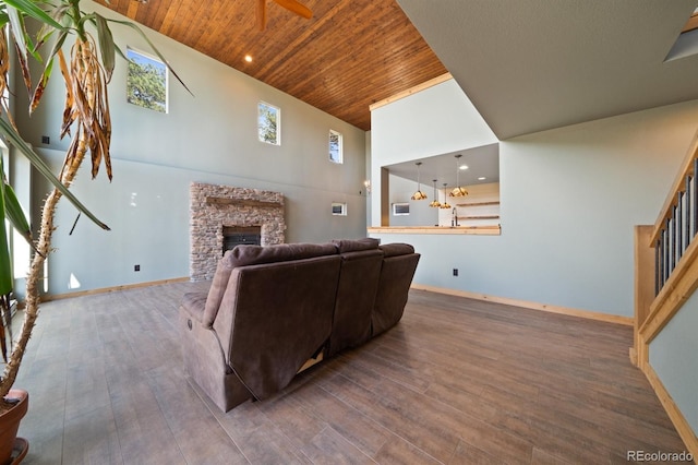 776 Hilltop Rd, Palmer Lake, CO 80133 - living room with wood ceiling, a towering ceiling, ceiling fan, a stone fireplace, and wood finished floors