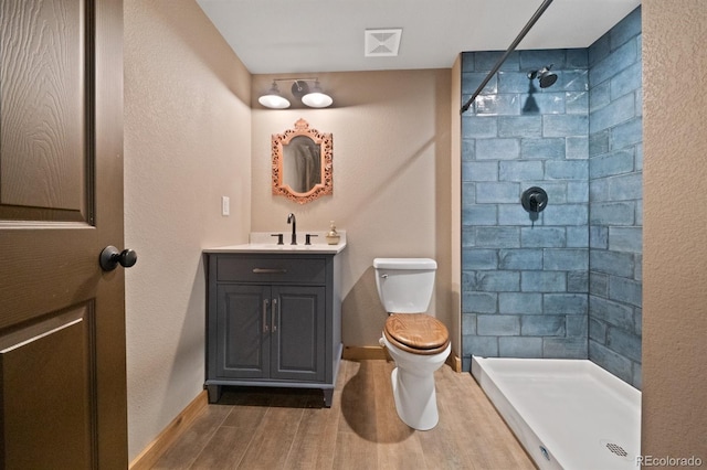 776 Hilltop Rd, Palmer Lake, CO 80133 - bathroom featuring visible vents, a tile shower, toilet, wood finished floors, and vanity