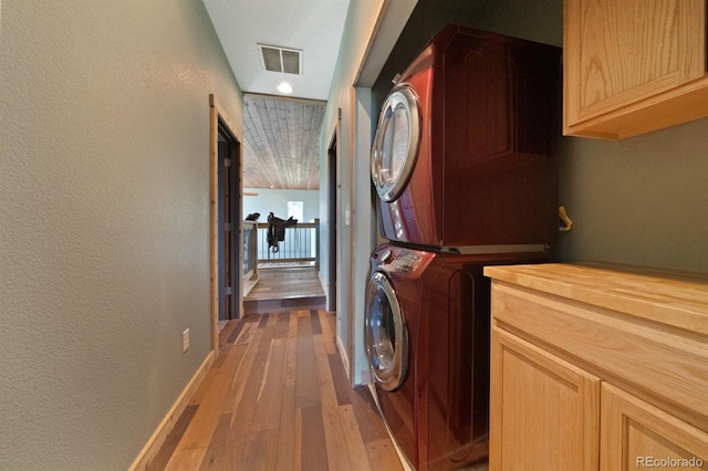 776 Hilltop Rd, Palmer Lake, CO 80133 - clothes washing area with wood finished floors, stacked washing maching and dryer, visible vents, cabinet space, and a textured wall