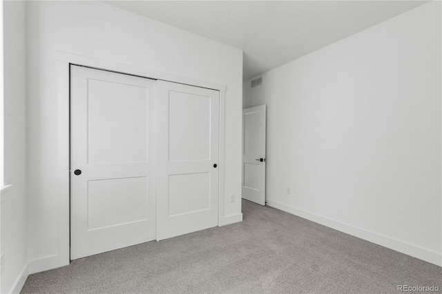 unfurnished bedroom featuring light carpet, a closet, and baseboards