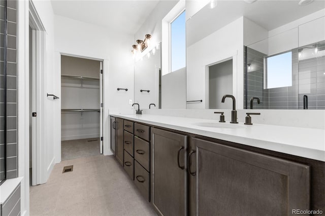 bathroom with double vanity, a walk in closet, and an enclosed shower