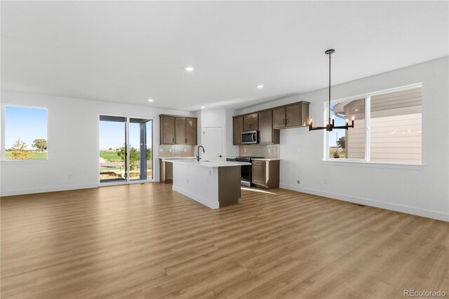 kitchen with appliances with stainless steel finishes, open floor plan, light countertops, light wood-style floors, and recessed lighting