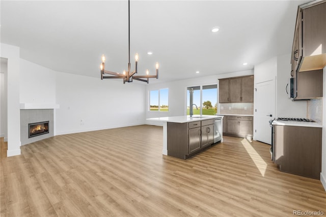 kitchen with appliances with stainless steel finishes, light countertops, open floor plan, a sink, and a kitchen island with sink