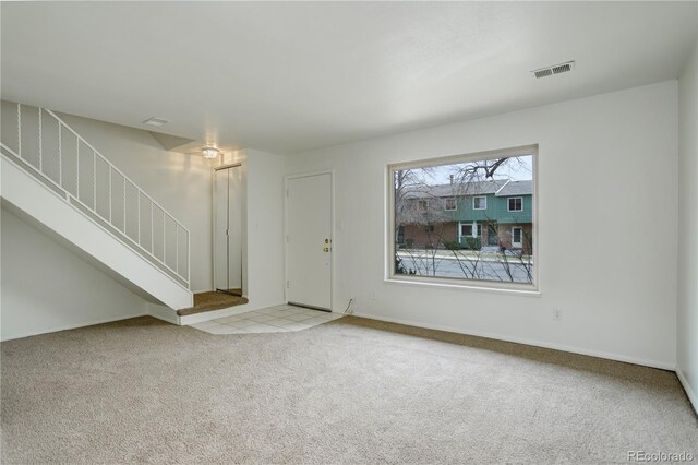 unfurnished living room with stairs, visible vents, carpet floors, and baseboards