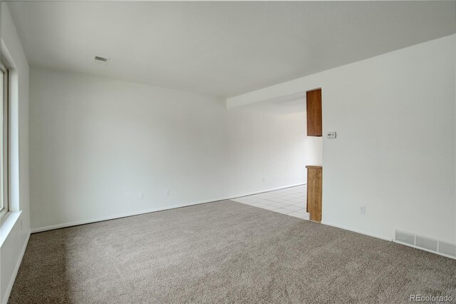 tiled spare room featuring visible vents and carpet