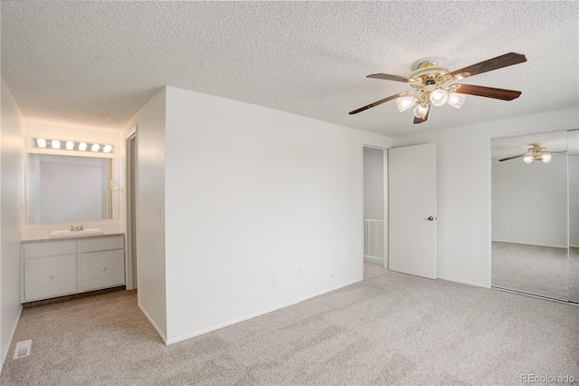 unfurnished bedroom with visible vents, a textured ceiling, a sink, and carpet