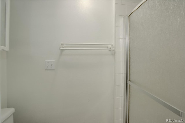 full bathroom featuring toilet and a shower with door