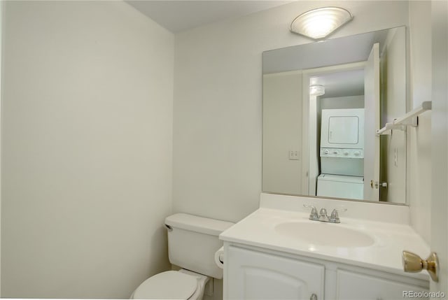 bathroom featuring toilet, vanity, and stacked washing maching and dryer