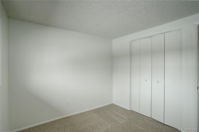 unfurnished bedroom with carpet flooring, baseboards, a closet, and a textured ceiling