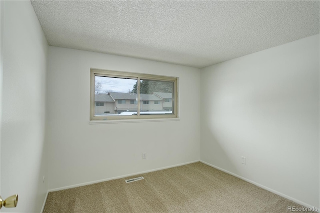 carpeted empty room with baseboards, visible vents, and a textured ceiling