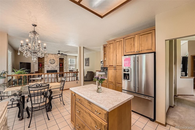 kitchen with high end refrigerator, light tile patterned floors, a center island, light countertops, and open floor plan