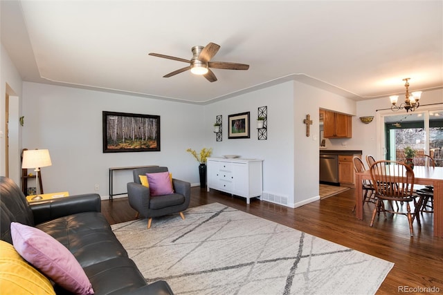 living area with visible vents, baseboards, dark wood finished floors, and ceiling fan with notable chandelier