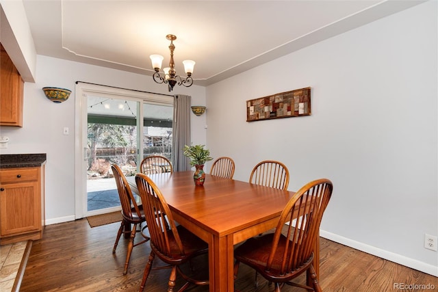 dining room featuring baseboards, dark wood-type flooring, and a notable chandelier