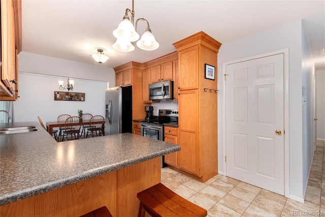 kitchen with dark countertops, appliances with stainless steel finishes, a peninsula, an inviting chandelier, and a sink