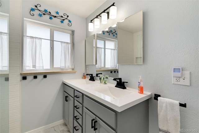 full bathroom with a sink, baseboards, marble finish floor, and double vanity