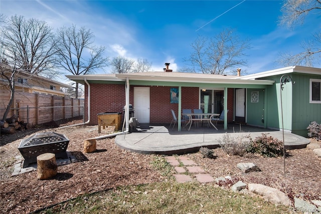 back of property with a patio, fence, brick siding, and an outdoor fire pit