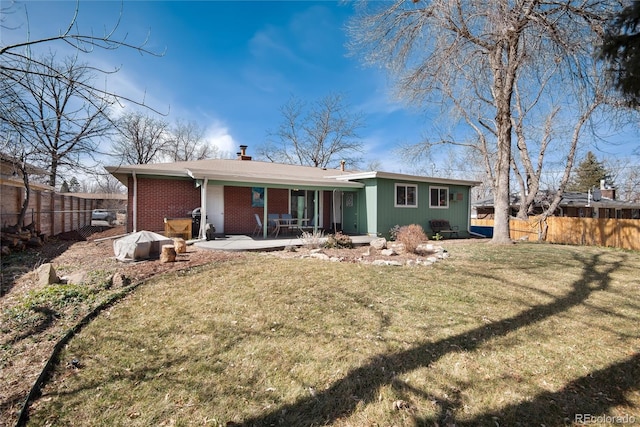 back of house featuring a lawn, a patio, fence, brick siding, and a chimney