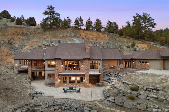 back house at dusk featuring a patio