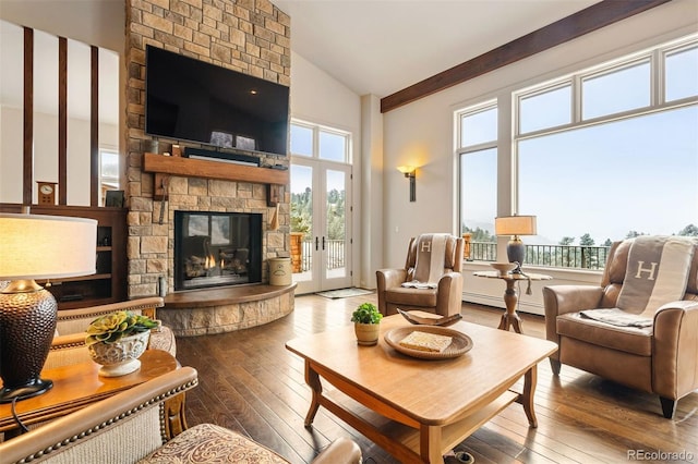 living room featuring a stone fireplace, a healthy amount of sunlight, hardwood / wood-style floors, and high vaulted ceiling