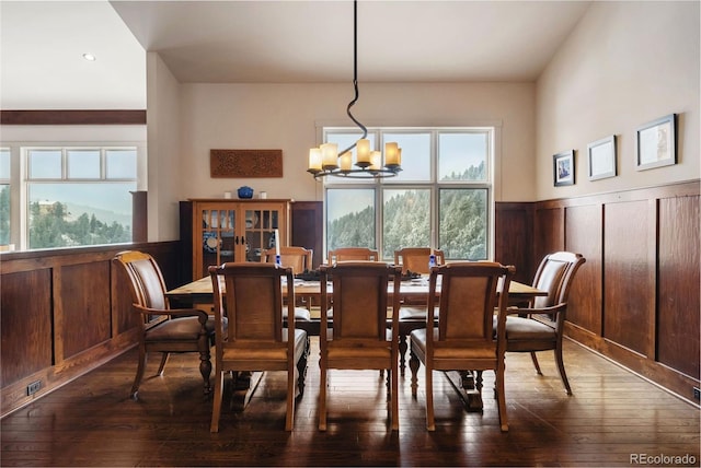 dining area with a chandelier, dark hardwood / wood-style flooring, and wood walls