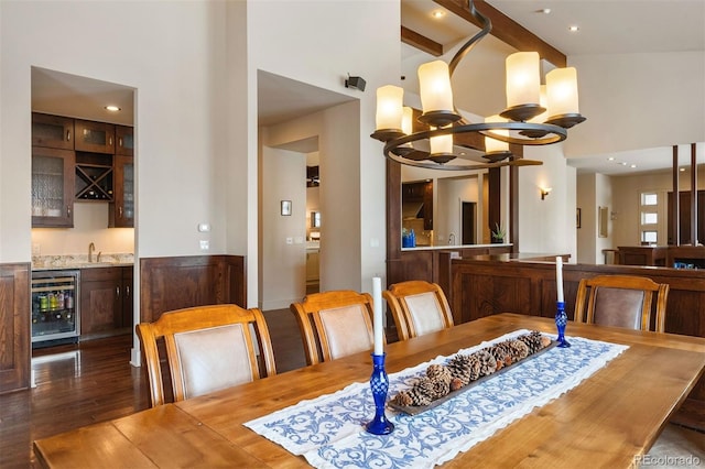 dining room with dark wood-type flooring, a towering ceiling, beverage cooler, and wet bar