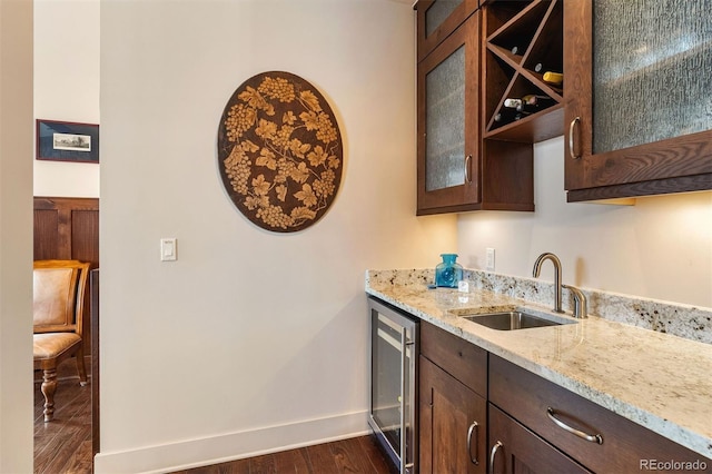 kitchen with sink, dark brown cabinets, dark hardwood / wood-style floors, beverage cooler, and light stone countertops