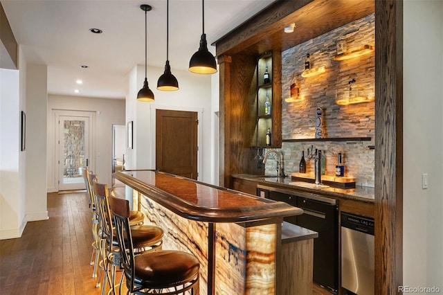 bar with sink, decorative light fixtures, dark brown cabinets, dark hardwood / wood-style floors, and dishwasher