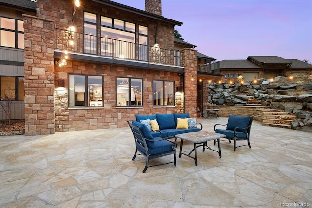 patio terrace at dusk featuring an outdoor living space and a balcony