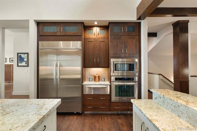 21609 Clarence Ln, Golden, CO 80401 - kitchen featuring built in appliances, a warming drawer, dark wood finished floors, light stone countertops, and backsplash