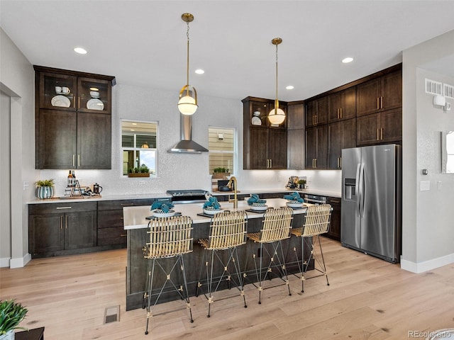 kitchen with a breakfast bar, stainless steel fridge with ice dispenser, and light hardwood / wood-style floors