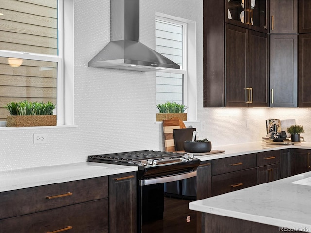 kitchen featuring dark brown cabinets, stainless steel range with gas cooktop, and wall chimney range hood