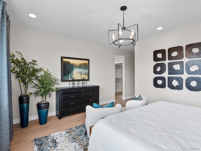 bedroom featuring a walk in closet, a closet, light hardwood / wood-style floors, and a notable chandelier