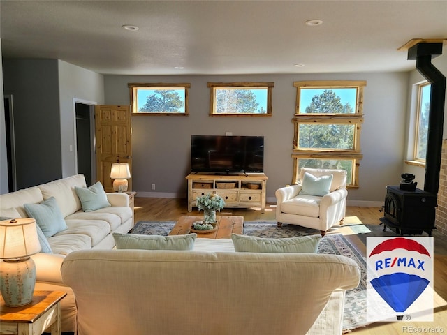 living room with a wood stove, light wood-style flooring, baseboards, and recessed lighting