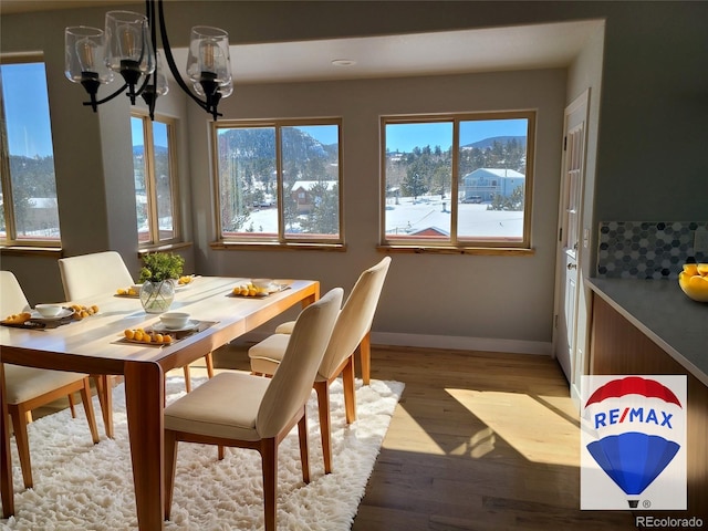 dining space with light wood finished floors, a mountain view, baseboards, and a chandelier