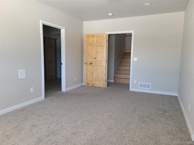 unfurnished bedroom with carpet, a walk in closet, visible vents, and baseboards