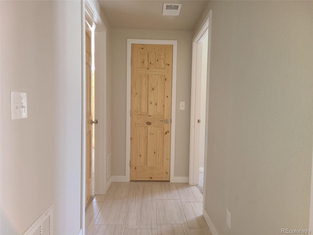 hall with light tile patterned floors, visible vents, and baseboards