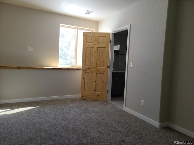 unfurnished room with carpet, visible vents, and baseboards