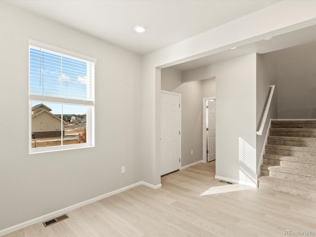 spare room featuring visible vents, baseboards, wood finished floors, and stairs